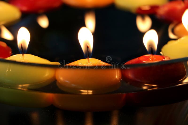 Circle of many candles in colors: yellow and orange red Close-up image. Floating above water. In a bowl. celebration. royalty free stock photo