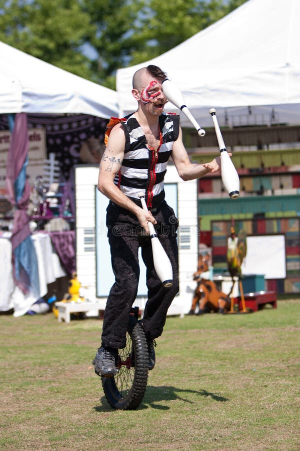 Circus Performer Juggles while Riding Unicycle Editorial Stock Photo