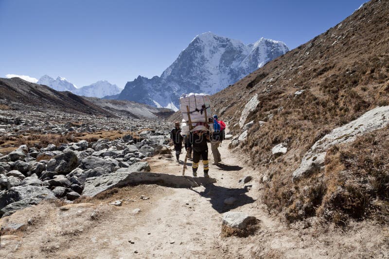 Cirka November, 2017 van Himalayagebergte, Nepal: wandelaars en portiers op de manier aan Everest-Basiskamp, mooi zonnig weer en royalty-vrije stock fotografie Cirka November, 2017 van Himalayagebergte, Nepal: wandelaars en portiers op de manier aan Everest-Basiskamp, mooi zonnig weer en royalty-vrije stock fotografie