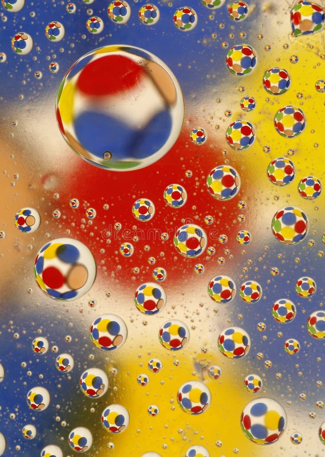 Water drops of various sizes on glass with a background with red, yellow and blue circles. Water drops of various sizes on glass with a background with red, yellow and blue circles.