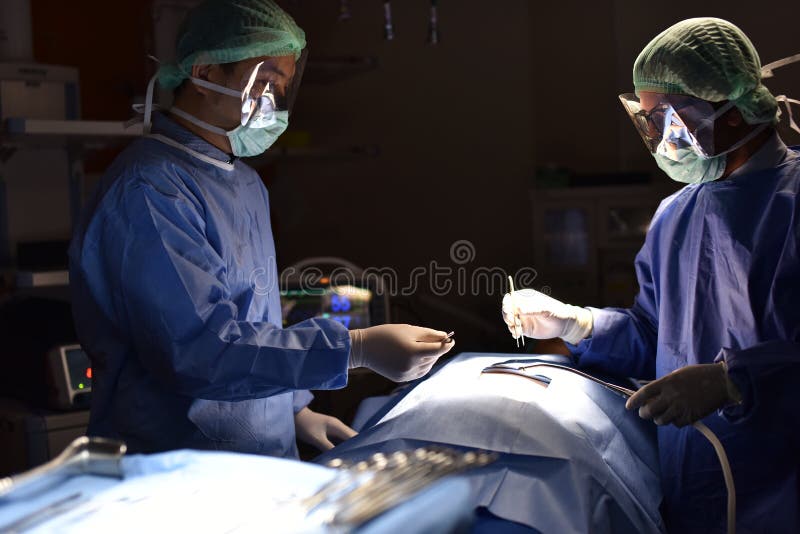 Cirujano de las personas en el trabajo en sala de operaciones Luz quirúrgica en la sala de operaciones imagen de archivo libre de regalías Cirujano de las personas en el trabajo en sala de operaciones Luz quirúrgica en la sala de operaciones imagen de archivo libre de regalías