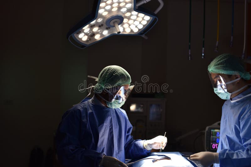 Cirujano de las personas en el trabajo en sala de operaciones Luz quirúrgica en la sala de operaciones imagen de archivo libre de regalías Cirujano de las personas en el trabajo en sala de operaciones Luz quirúrgica en la sala de operaciones imagen de archivo libre de regalías