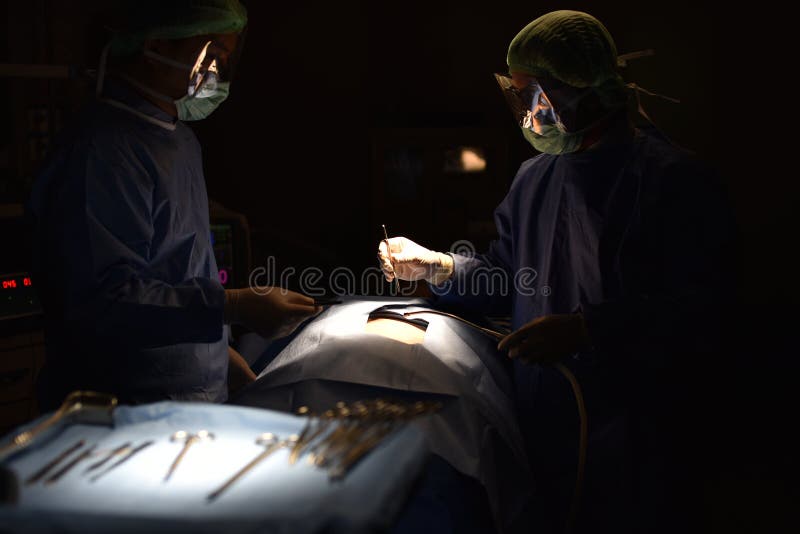 Cirujano de las personas en el trabajo en sala de operaciones Luz quirúrgica en la sala de operaciones imagen de archivo Cirujano de las personas en el trabajo en sala de operaciones Luz quirúrgica en la sala de operaciones imagen de archivo