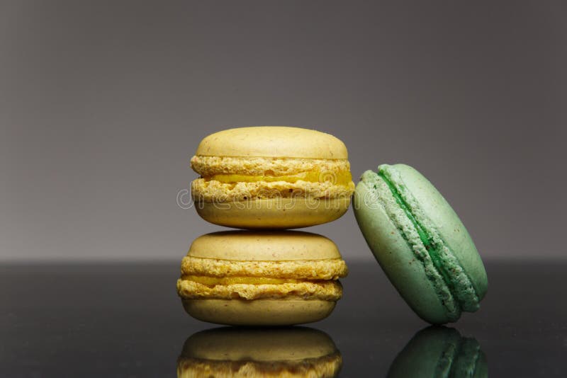 Citron- och mintkaramellmacarons på ett exponeringsglas med reflexion arkivbild Citron- och mintkaramellmacarons på ett exponeringsglas med reflexion arkivbild
