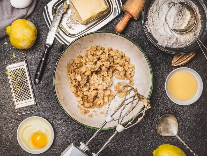 Citronkaka- eller kakaförberedelse med matlagningingredienser Breda smör på och sockra blandning med handblandaren på mörk köksbo royaltyfria bilder Citronkaka- eller kakaförberedelse med matlagningingredienser Breda smör på och sockra blandning med handblandaren på mörk köksbo royaltyfria bilder