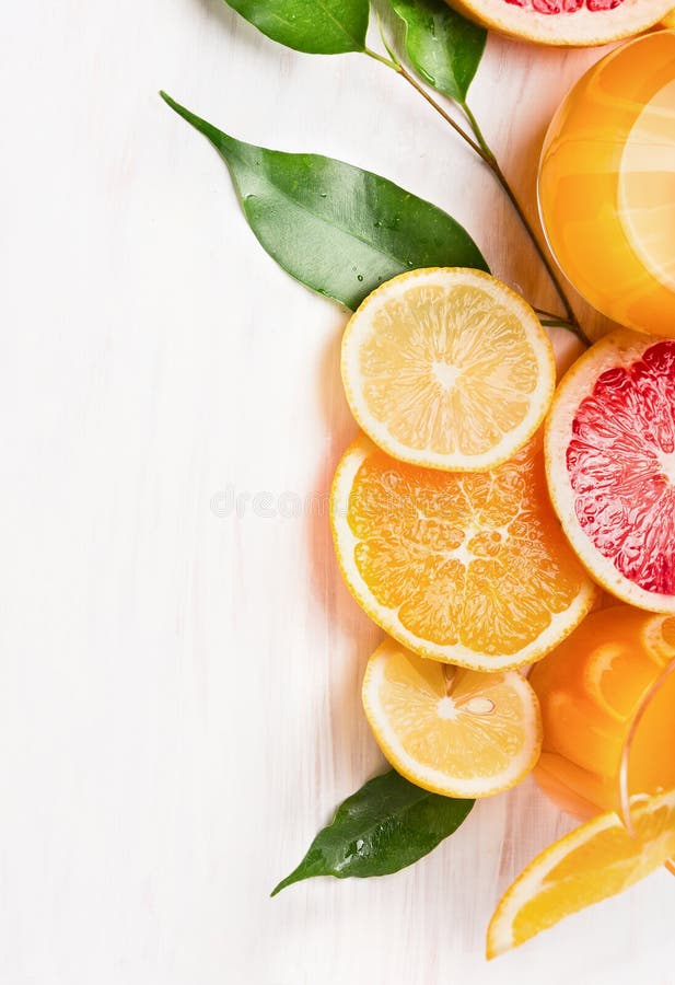 Citrus juice and sliced fruits: orange, lemon and grapefruit on white wooden