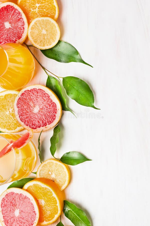 Citrusfrukter med gröna sidor och exponeringsglas med fruktsaft på den vita trätabellen, ram royaltyfri foto Citrusfrukter med gröna sidor och exponeringsglas med fruktsaft på den vita trätabellen, ram royaltyfri foto