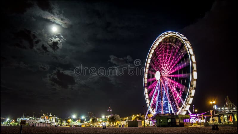 Citscape e praia da noite de Timelapse Ferris Wheel com Lua cheia