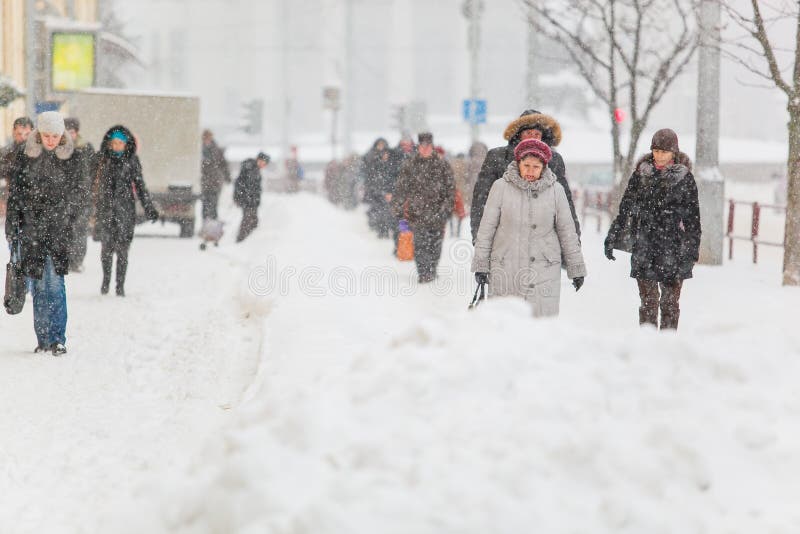 Cittadini che vanno lungo il marciapiede nella bufera di neve pesante in città fotografia stock libera da diritti Cittadini che vanno lungo il marciapiede nella bufera di neve pesante in città fotografia stock libera da diritti
