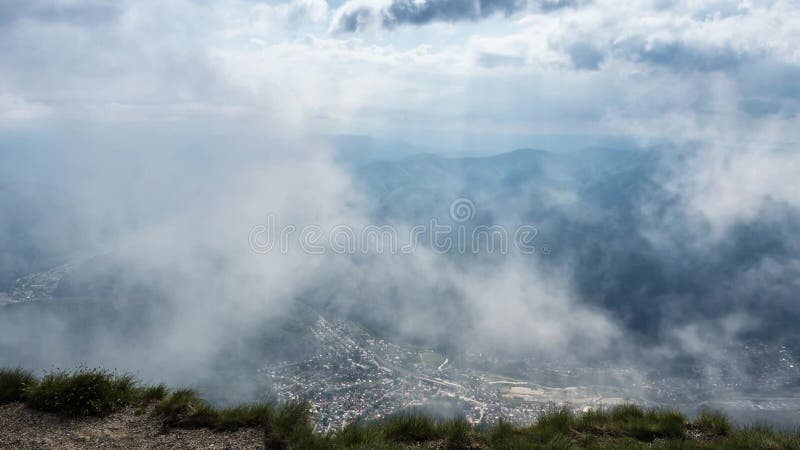 Città sotto la montagna con il cielo nuvoloso e la nebbia