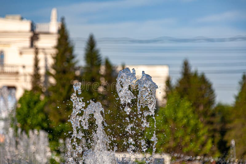 City fountain with splashes and jets of water against the background of buildings and green trees under a blue sky on a clear royalty free stock photos City fountain with splashes and jets of water against the background of buildings and green trees under a blue sky on a clear royalty free stock photos