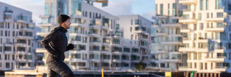 City lifestyle winter run runner athlete man jogging outside on modern apartment building background panoramic banner