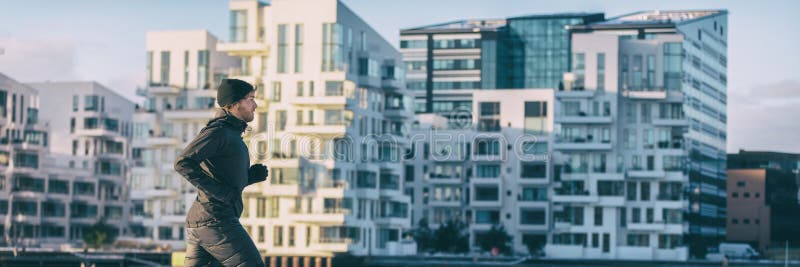 City lifestyle winter run runner athlete man jogging outside on modern apartment building background panoramic banner