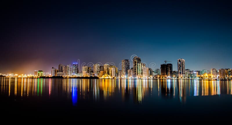City at night reflected on ocean stock photography