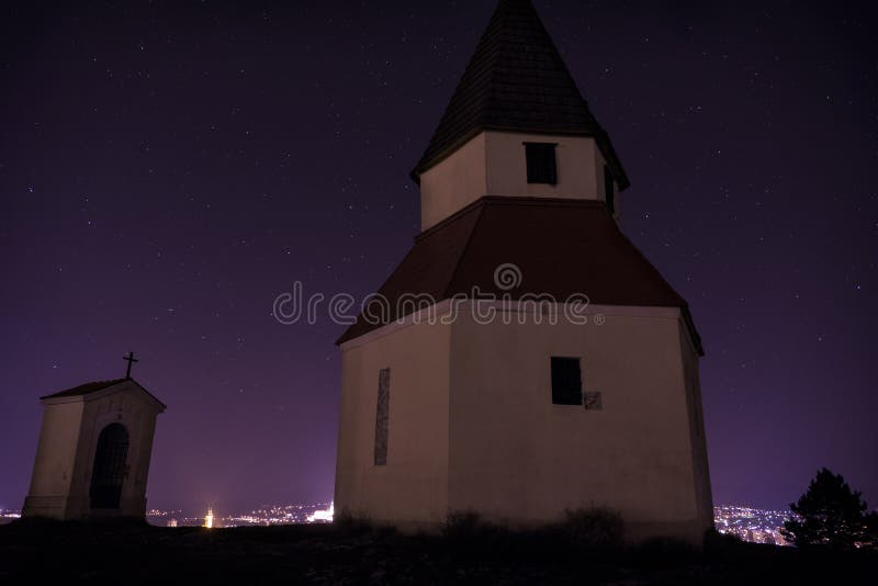 City night from the view point on top of Hill with chapel. Slovak city Nitra with purple night sky with stars and with church. Cit