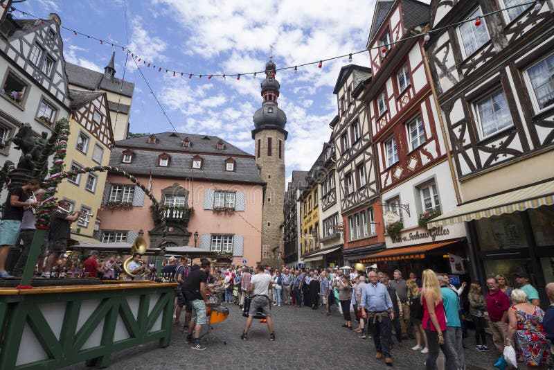 Cochem, RHINELAND-PALATINATE/ GERMANY - Aug 20, 2016: Cityscape of Cochem with its typical half-timbered houses and restaurants. Market square with town hall in background, people celebrating and music band playing.