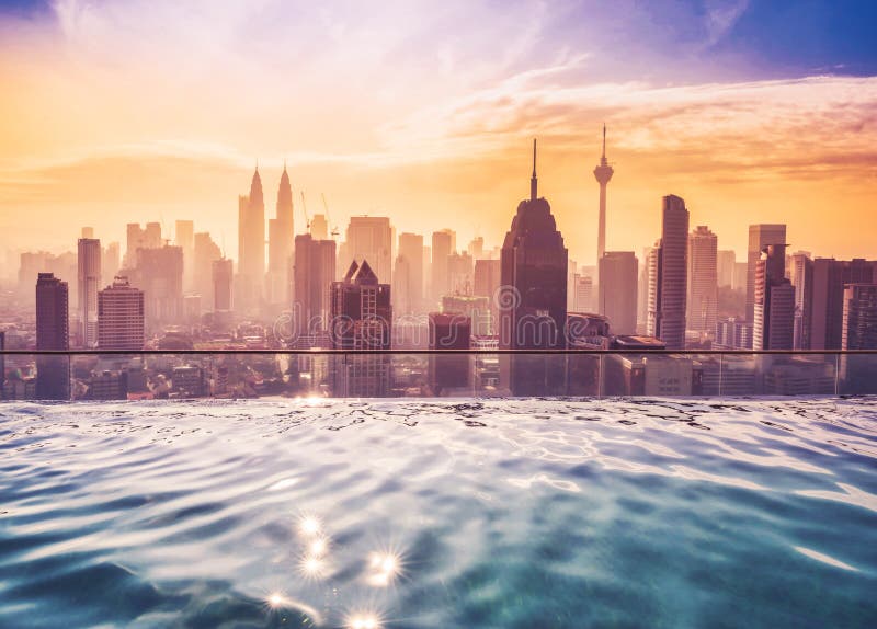 Cityscape of Kuala lumpur city skyline with swimming pool on the roof top of hotel at sunrise in Malaysia