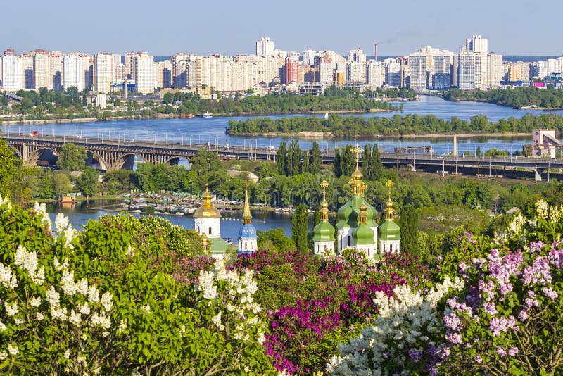 Paisaje urbano de kiev monasterio, puente a través de un rio, a lila flor en botánico jardín.