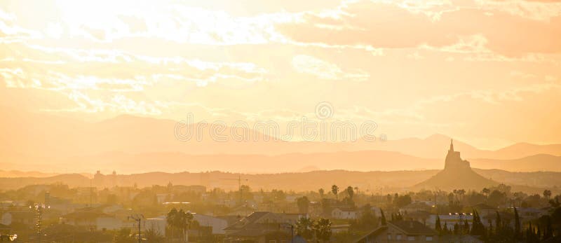 Cityscape of Murcia during a foggy sunset. Silhouettes of cathedral, monteagudo, towers and buildings in Murcia city, Spain