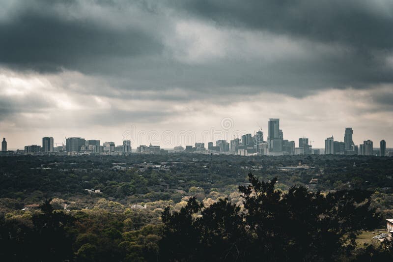 A Dark Sky Over a City that Has Trees Growing in the Foreground Stock