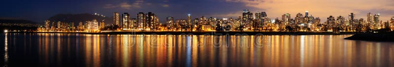 The Vancouver downtown at night glittering against a backdrop of dark mountains. Vancouver skyscraper stock images, royalty-free photos and pictures