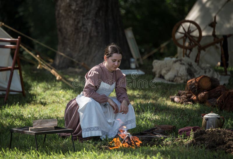 A young woman sets a fire for cooking at a Civil War era camp in northern California. A young woman sets a fire for cooking at a Civil War era camp in northern California.