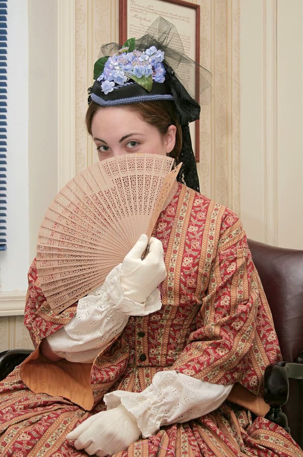 Young woman with a fan dressed in 1860s style clothing. Young woman with a fan dressed in 1860s style clothing