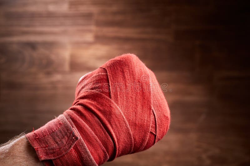 Ciérrese encima de la imagen del puño de un boxeador con el vendaje rojo contra fondo marrón fotos de archivo libres de regalías Ciérrese encima de la imagen del puño de un boxeador con el vendaje rojo contra fondo marrón fotos de archivo libres de regalías