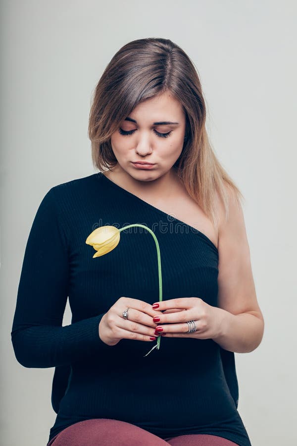Ciérrese encima de la mujer joven triste que detiene a Rose Flower While Looking muerta en la cámara fotos de archivo libres de regalías Ciérrese encima de la mujer joven triste que detiene a Rose Flower While Looking muerta en la cámara fotos de archivo libres de regalías