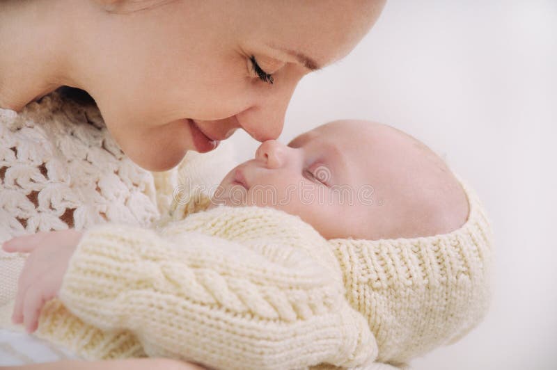 Close up mother's face touching nose by nose of her baby; happy family concept; sleeping cute baby; maternity concept; mother and her newborn baby. Close up mother's face touching nose by nose of her baby; happy family concept; sleeping cute baby; maternity concept; mother and her newborn baby