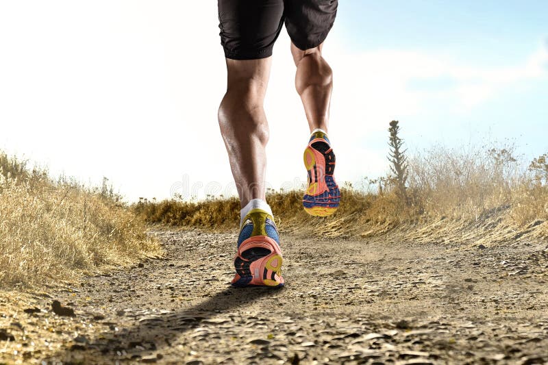 Ciérrese encima de pies con las zapatillas deportivas y las piernas atléticas fuertes del hombre del deporte que activan en entre foto de archivo libre de regalías