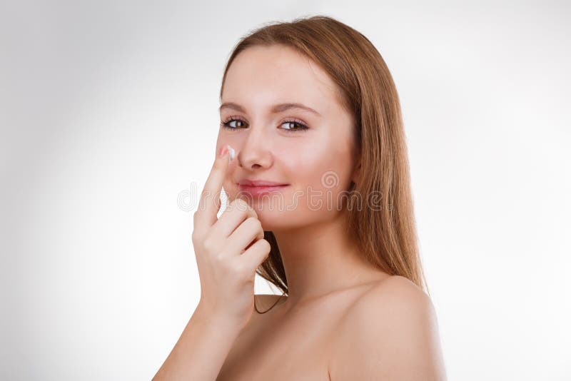 Ciérrese encima del retrato de la muchacha sonriente feliz joven hermosa que aplica la crema en su nariz imágenes de archivo libres de regalías Ciérrese encima del retrato de la muchacha sonriente feliz joven hermosa que aplica la crema en su nariz imágenes de archivo libres de regalías