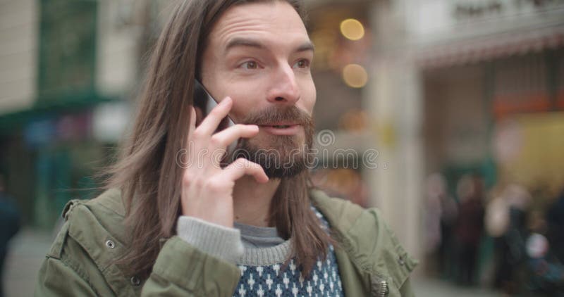 Ciérrese encima del retrato del hombre del inconformista que hace llamada de teléfono al aire libre en una ciudad