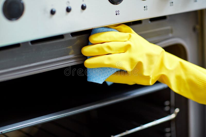 Ciérrese para arriba de cocina del horno de la limpieza de la mujer en casa fotografía de archivo Ciérrese para arriba de cocina del horno de la limpieza de la mujer en casa fotografía de archivo