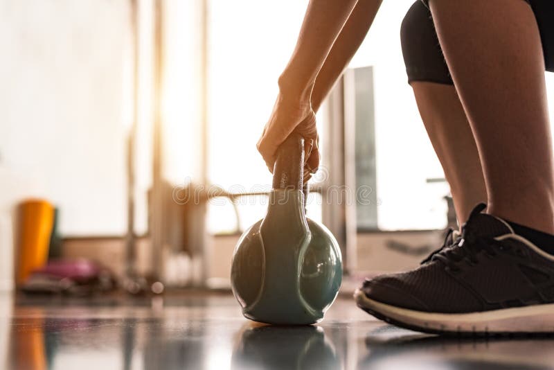 Ciérrese para arriba de kettlebell de elevación de la mujer como pesas de gimnasia en centro de formación del gimnasio del club d foto de archivo libre de regalías Ciérrese para arriba de kettlebell de elevación de la mujer como pesas de gimnasia en centro de formación del gimnasio del club d foto de archivo libre de regalías