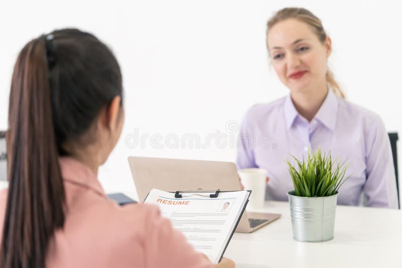 Ciérrese para arriba de la entrevista de trabajo que se centra en la mujer que da el curriculum vitae con la oficina fotografía de archivo Ciérrese para arriba de la entrevista de trabajo que se centra en la mujer que da el curriculum vitae con la oficina fotografía de archivo