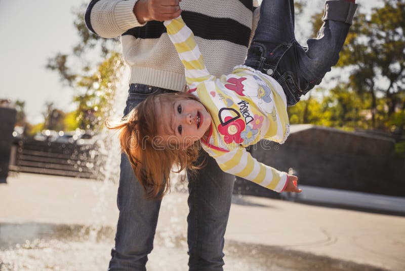 Ciérrese para arriba de la familia cariñosa alegre feliz, madre y la pequeña hija que juega en parque al lado de la fuente, madre fotos de archivo libres de regalías Ciérrese para arriba de la familia cariñosa alegre feliz, madre y la pequeña hija que juega en parque al lado de la fuente, madre fotos de archivo libres de regalías