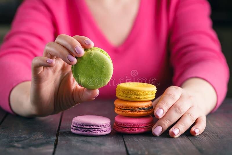 Ciérrese para arriba de la mano femenina de los pasteles que cocina los macarrones deliciosos fotos de archivo libres de regalías Ciérrese para arriba de la mano femenina de los pasteles que cocina los macarrones deliciosos fotos de archivo libres de regalías