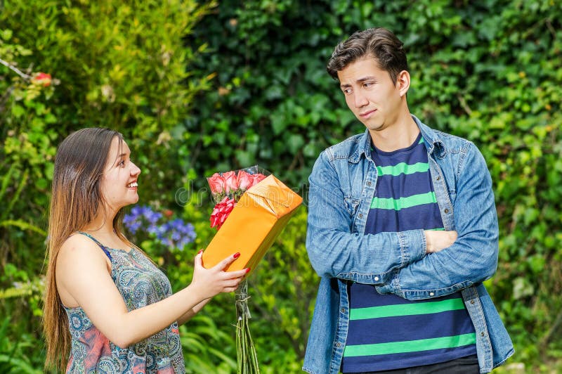 Ciérrese para arriba de la mujer feliz que sostiene un regalo y las flores que miran su agolpamiento y muchacho con sus brazos cr imagenes de archivo Ciérrese para arriba de la mujer feliz que sostiene un regalo y las flores que miran su agolpamiento y muchacho con sus brazos cr imagenes de archivo