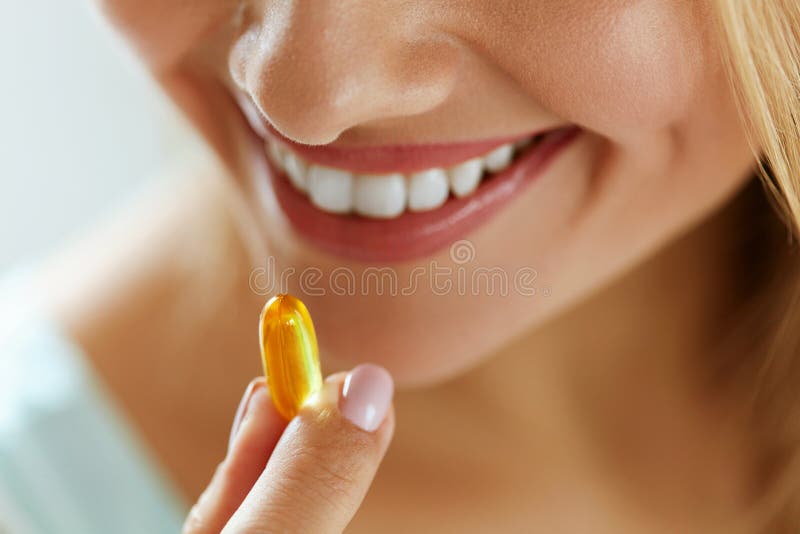 Ciérrese para arriba de la mujer hermosa que toma la cápsula del aceite de pescado en boca foto de archivo Ciérrese para arriba de la mujer hermosa que toma la cápsula del aceite de pescado en boca foto de archivo