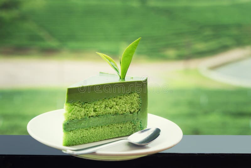 Ciérrese para arriba de la torta fresca del té verde en la placa blanca con la plantación de té en fondo foto de archivo libre de regalías Ciérrese para arriba de la torta fresca del té verde en la placa blanca con la plantación de té en fondo foto de archivo libre de regalías