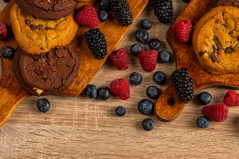 Ciérrese para arriba de las galletas oscuras del chocolate con la mezcla de frutas del bosque en la tabla de madera, con el copys imagen de archivo libre de regalías Ciérrese para arriba de las galletas oscuras del chocolate con la mezcla de frutas del bosque en la tabla de madera, con el copys imagen de archivo libre de regalías
