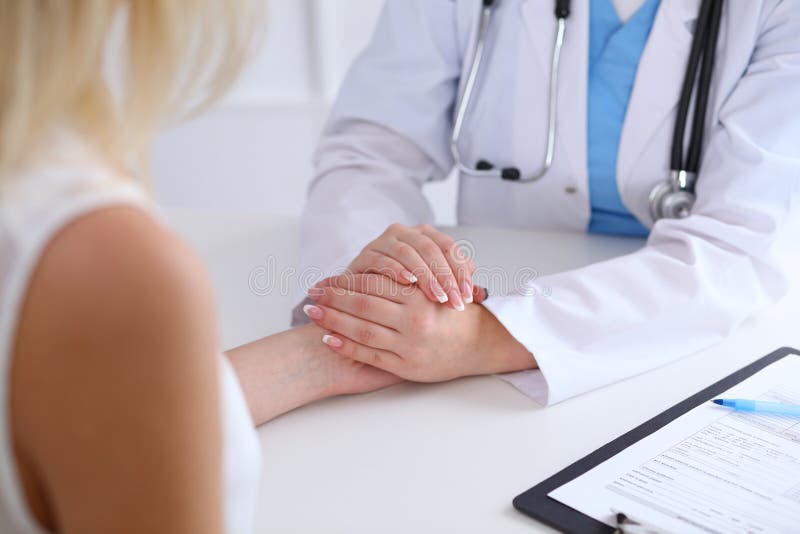 Ciérrese para arriba de las manos del doctor que tranquilizan a su paciente femenino fotografía de archivo libre de regalías Ciérrese para arriba de las manos del doctor que tranquilizan a su paciente femenino fotografía de archivo libre de regalías