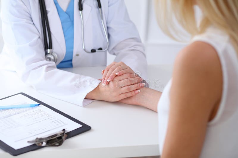 Ciérrese para arriba de las manos del doctor que tranquilizan a su paciente femenino imágenes de archivo libres de regalías Ciérrese para arriba de las manos del doctor que tranquilizan a su paciente femenino imágenes de archivo libres de regalías