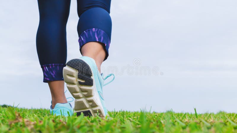 Ciérrese para arriba de las zapatillas deportivas del atleta de la mujer de la aptitud mientras que camina en el parque al aire foto de archivo libre de regalías
