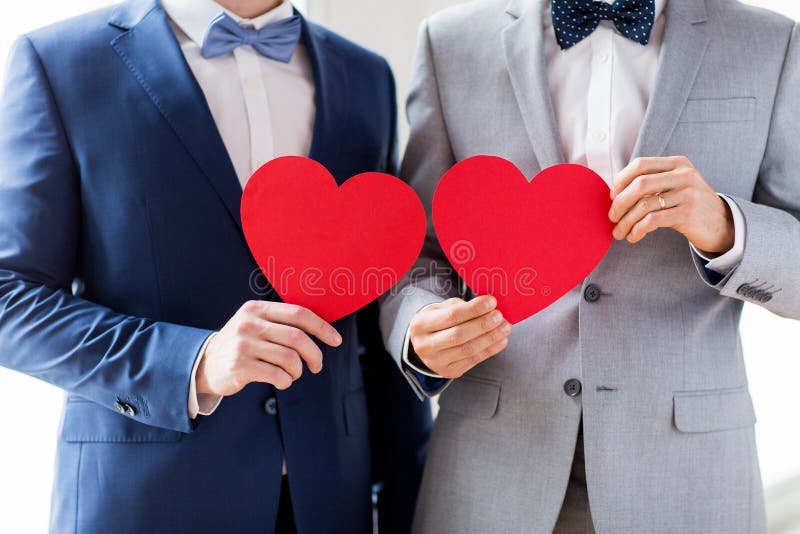 Ciérrese para arriba de los pares gay masculinos que llevan a cabo corazones rojos imagenes de archivo Ciérrese para arriba de los pares gay masculinos que llevan a cabo corazones rojos imagenes de archivo