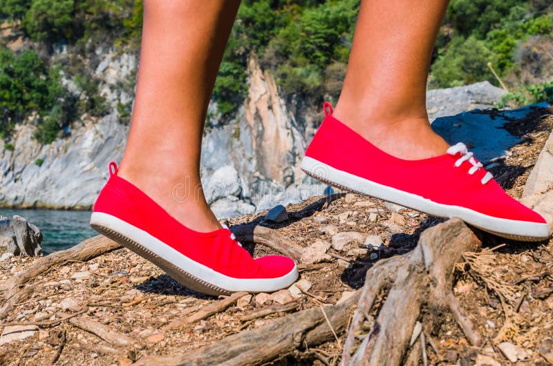 Ciérrese para arriba de los pies de una muchacha del turista que llevan los zapatos rojos que caminan en la isla del cefalonia, m imagenes de archivo Ciérrese para arriba de los pies de una muchacha del turista que llevan los zapatos rojos que caminan en la isla del cefalonia, m imagenes de archivo
