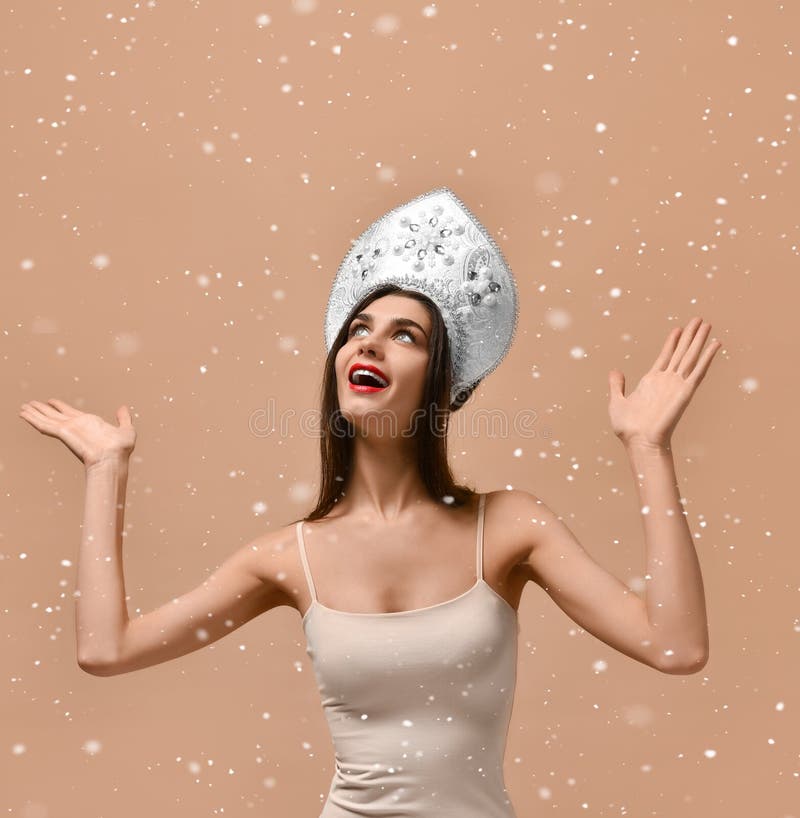 Ciérrese para arriba de muchacha de la mujer en el kokoshnik ruso tradicional del casquillo que sostiene nieve en manos en estudi foto de archivo Ciérrese para arriba de muchacha de la mujer en el kokoshnik ruso tradicional del casquillo que sostiene nieve en manos en estudi foto de archivo