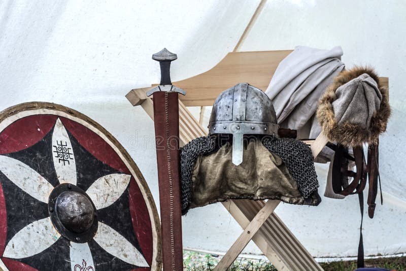 Ciérrese para arriba del equipo medieval del caballero en tienda vieja el dormir Casco del metal, escudo, espada imagen de archivo Ciérrese para arriba del equipo medieval del caballero en tienda vieja el dormir Casco del metal, escudo, espada imagen de archivo