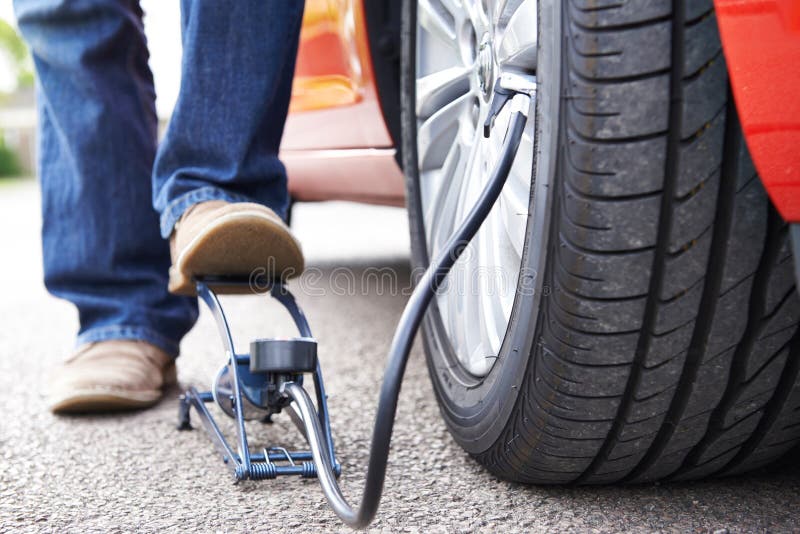 Ciérrese para arriba del hombre que infla el neumático del coche con la bomba de pie imagen de archivo Ciérrese para arriba del hombre que infla el neumático del coche con la bomba de pie imagen de archivo